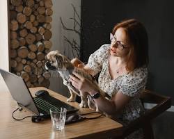 A friendly, professional veterinarian in scrubs holding a digital tablet while sitting with a happy dog during a pet care consultation.