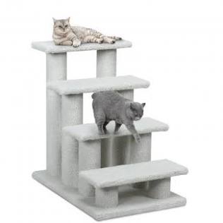 An older gray cat using pet steps to reach a comfortable resting place in a dimly lit room